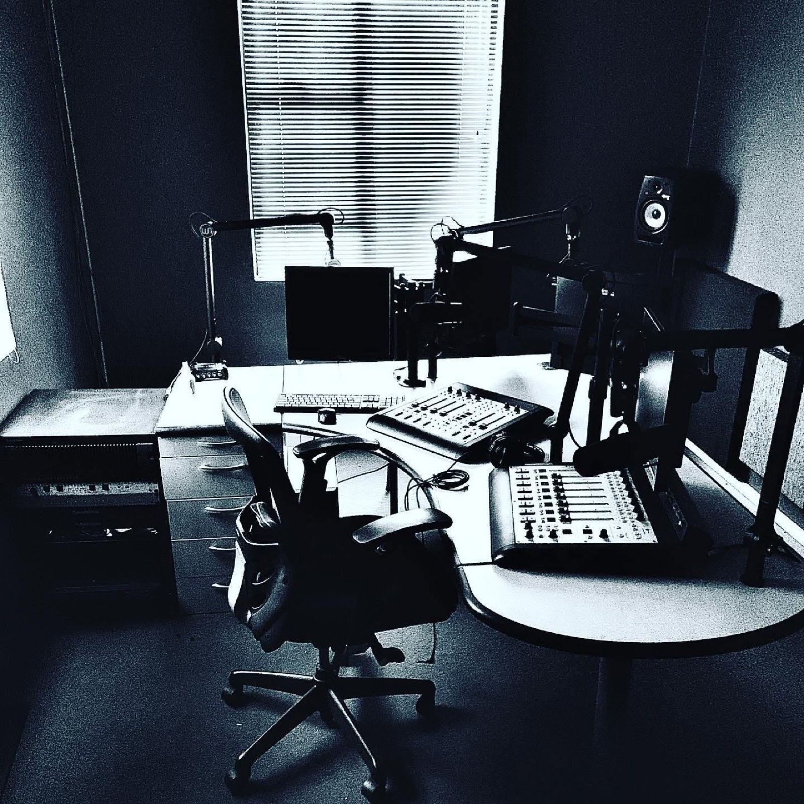 Modern broadcast studio desk with consoles, microphones, monitors, and rack-mounted equipment